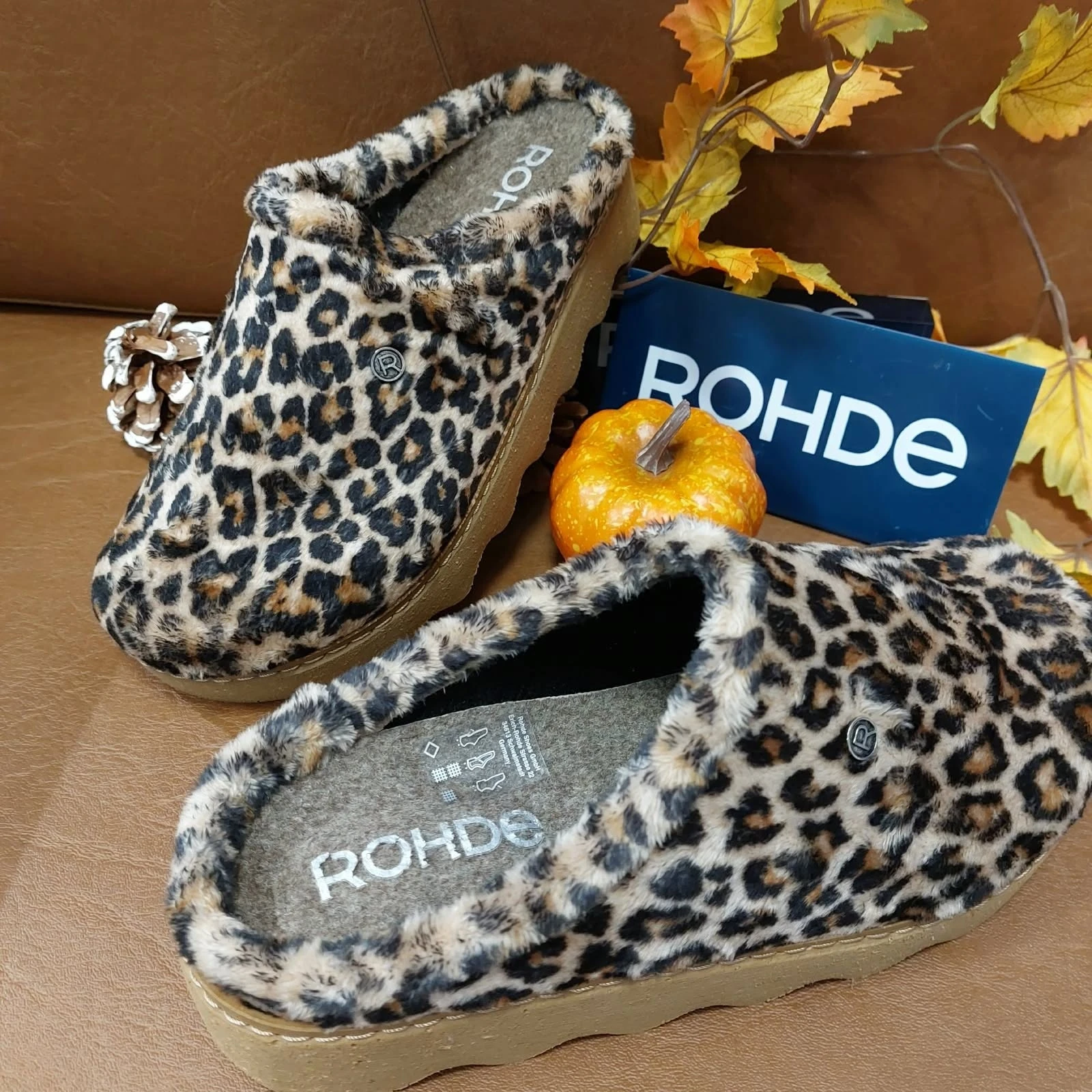 Rohde-pantoffels met panterprint en stevige zool, tussen herfstbladeren