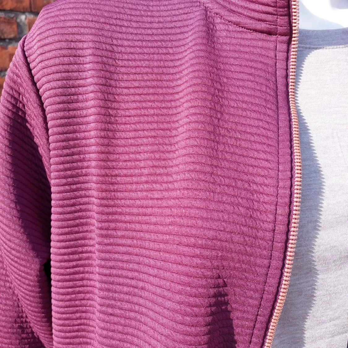 Close-up van de ribstructuur en de rits van het bordeaux Skechers-vest